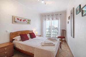 a bedroom with a bed and a chair and a window at Quarteira Beach I in Quarteira