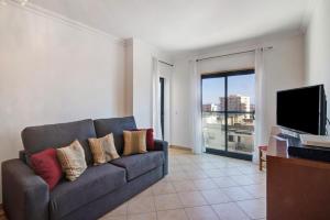 a living room with a couch and a flat screen tv at Quarteira Beach I in Quarteira