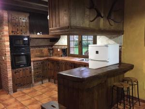 a kitchen with wooden cabinets and a white refrigerator at Los Avellanos Casa 3 in Celis