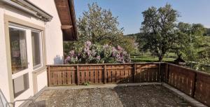 a wooden fence in front of a house with flowers at Ferienhof Hanssler in Wilhelmsdorf