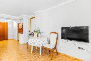 a dining room with a table and a television on a wall at Unique Apartahotel 3-2 in Torrevieja