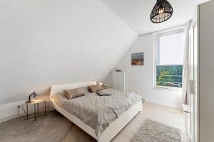 a white bedroom with a bed and a window at Küstenliebe-Fehmarn in Fehmarn