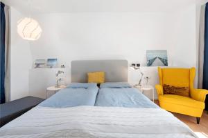 a bedroom with a large bed and a yellow chair at Hausboot Sutje in Großenbrode