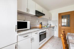 a kitchen with white cabinets and a microwave at Ferienhof Martens in Schülperweide