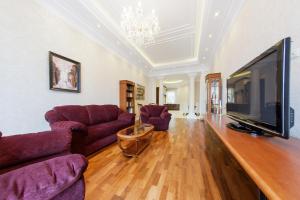 a living room with a large television and purple couches at hth24 apartments on Mohovaya 4 in Saint Petersburg