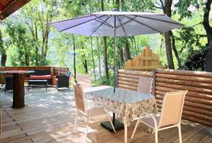 a table and chairs with an umbrella on a deck at Charmant petit chalet individuel in Briançon +8 photos