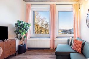 a living room with two large windows and a couch at Suiten im Alten Berghotel Antonia in Eslohe