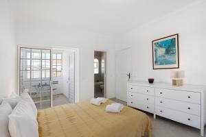 a white bedroom with a large bed and a mirror at Villa Galé in Guia