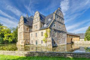 an old castle in the middle of a body of water at Ferienwohnung im Grünen in Bissendorf