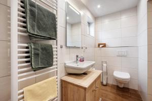 a white bathroom with a sink and a toilet at Ferienwohnung am Wiesenweg in Mauerstetten +14 photos