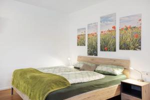 a bedroom with a bed with four paintings on the wall at Ferienwohnung am Wiesenweg in Mauerstetten