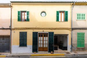 a building with green shuttered windows and a door at Sa Mina in Santa Margalida