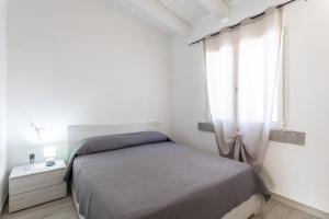 a white bedroom with a bed and a window at Casa Macis vista mare in Isola Rossa