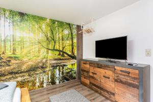 a living room with a tv and a forest wall mural at Ribeiro Tesouro in Friesenheim