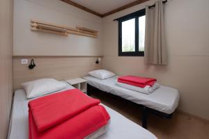a room with two beds with red sheets and a window at Chalet 35m2 - Armen in Plouhinec