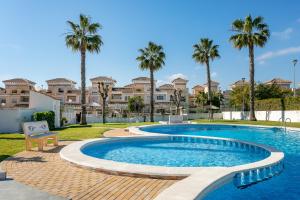 a swimming pool with palm trees and houses at Casa Susan in Torrevieja