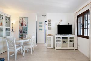 a white dining room with a table and a tv at Puerto Chico A in Playa Blanca