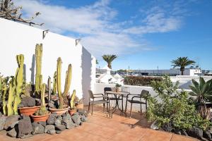 a patio with a table and chairs and cactus at Puerto Chico A in Playa Blanca