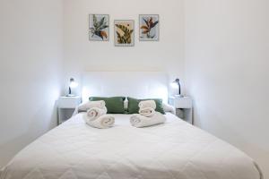 a white bedroom with a large white bed with towels at Dimora Biscari in Acate