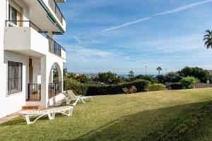 a white house with two benches on the grass at Superbly situated Vistamar in Mijas Costa
