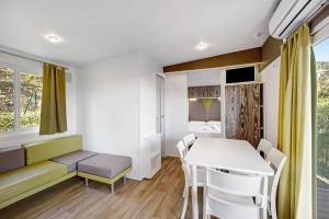 a living room with a table and chairs and a room with a bed at Mobile Home Alloro 165 in Pietra Ligure