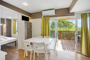 a dining room with a table and chairs and a balcony at Mobile Home Alloro 165 in Pietra Ligure
