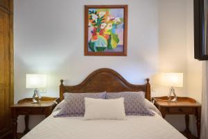 a bedroom with a bed with two lamps and a painting at Finca La Rubina in Teguise