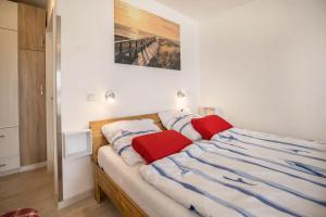 a bed with two red pillows on top of it at Ferienwohnung Seestern in Norderney