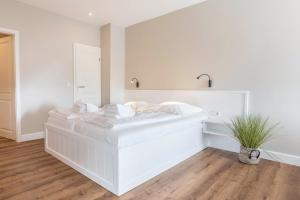 a white bed in a room with a potted plant at Strandburg in Westerland