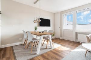 a dining room with a wooden table and white chairs at Strandburg in Westerland
