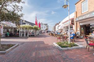 a street in a town with tables and chairs at Strandburg in Westerland