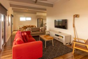 a living room with a red couch and a tv at River Vista at Aruma in Walker Flat