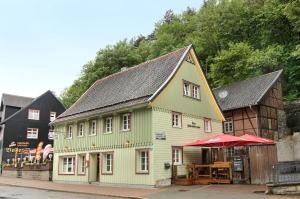 a green and yellow building with a red umbrella at Altes Höhlenführerhaus in Rübeland