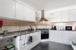 a kitchen with white cabinets and a sink at Apartamento Fénix Garajau in Caniço