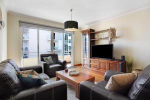 a living room with leather furniture and a flat screen tv at Apartamento Fénix Garajau in Caniço