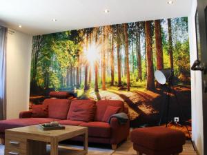 a living room with a red couch in a forest mural at Ferienwohnung Niggemann in Bestwig