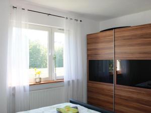 a bedroom with a large wooden cabinet and a window at Ferienwohnung Niggemann in Bestwig