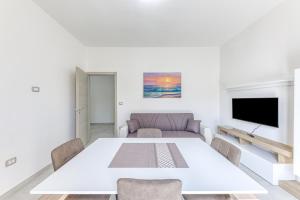 a white dining room with a table and a couch at Messapica Rooms in Ugento