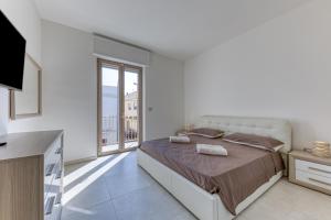 a white bedroom with a bed and a large window at Messapica Rooms in Ugento