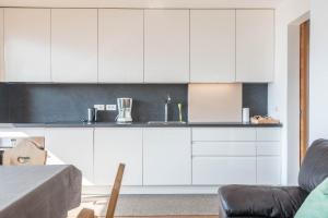 a white kitchen with white cabinets and a table at Thalerhof App Melisse in Feldthurns