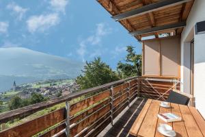 a balcony with a wooden table and a view at Thalerhof App Melisse in Feldthurns