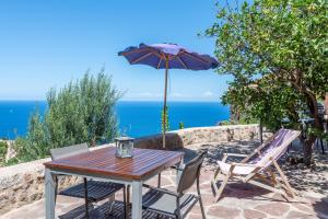 a table and chairs with an umbrella and the ocean at Little Paradise in Banyalbufar in Banyalbufar