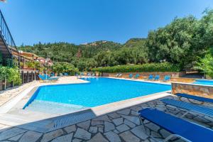 a swimming pool with blue chairs and a resort at Arianna apartment 10 in Paleokastritsa