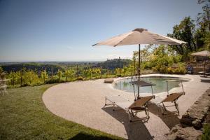 a table and two chairs with an umbrella next to a pool at Cascina Voglietti - Private Pool in Murisengo