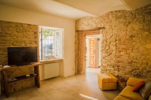 a living room with a tv and a stone wall at Cascina Voglietti - Private Pool in Murisengo