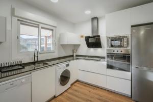 a kitchen with white cabinets and a stainless steel refrigerator at Casa La Isi in Rades de Abajo +20 photos