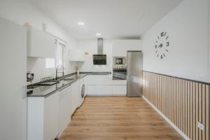 a kitchen with white cabinets and a wooden floor at Casa La Isi in Rades de Abajo
