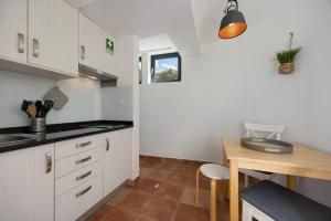 a kitchen with white cabinets and a wooden table at Apartment Amado - Carrapateira in Carrapateira