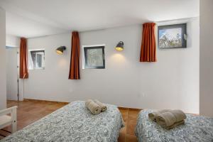 two beds in a room with red curtains at Apartment Amado - Carrapateira in Carrapateira +3 photos