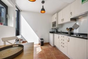 a kitchen with white cabinets and a wooden table at Apartment Amado - Carrapateira in Carrapateira